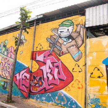 Artistas: Meduza e Vitones. Descrição: Muro externo amarelo apresenta grafitti com