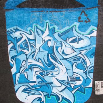 Foto: Júlia Dávila. Artista: Does. Descrição: Muro externo preto apresenta grafitti de lata de lixo azul, dentro dela diversos desenhos de formas orgânicas.
