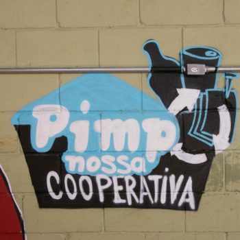 Artista: Snak 13. Descrição: Muro externo marrom apresenta grafitti do logo do pimp nossa cooperativa
