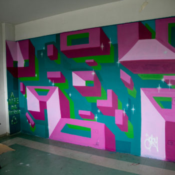 Artista: Barbara Goy. Descrição: Parede interna da Cooperativa Central Tietê apresenta mural artístico com figuras geométricas e abstratas. As figuras são retangulares e coloridas.