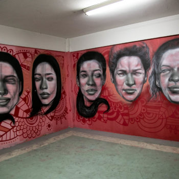 Artista: Tito Ferrara. Descrição: Parede interna da Cooperativa Central Tietê apresenta mural artístico de rostos de mulheres. As mulheres são reproduções de fotos das cooperadas.
